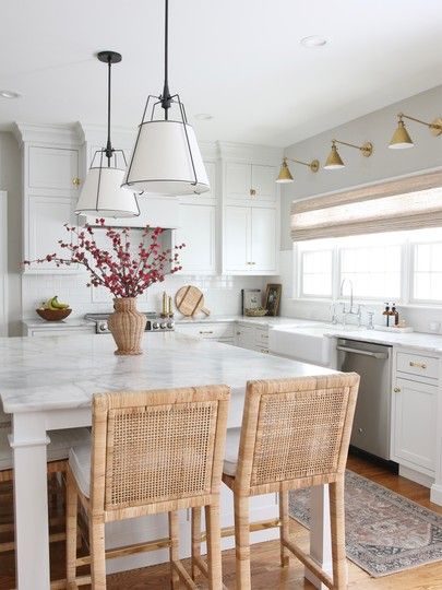 a kitchen with two chairs and a table in the center, surrounded by white cabinets