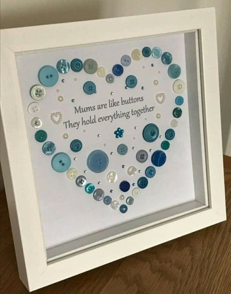 a white frame with buttons in the shape of a heart on top of a wooden table