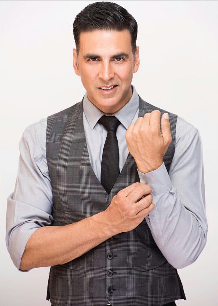 a man in a suit and tie posing for the camera with his hand on his chest