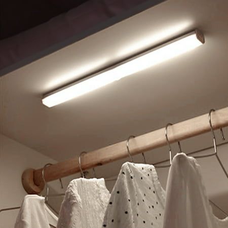 clothes hanging on a rail in a room with light coming from the ceiling above them