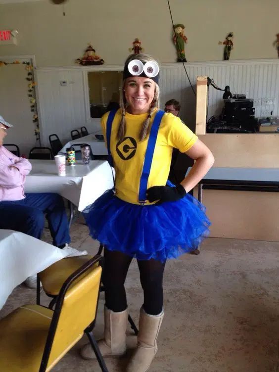 a woman in a minion costume standing next to a table