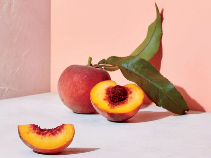 two peaches with one cut in half sitting on a table