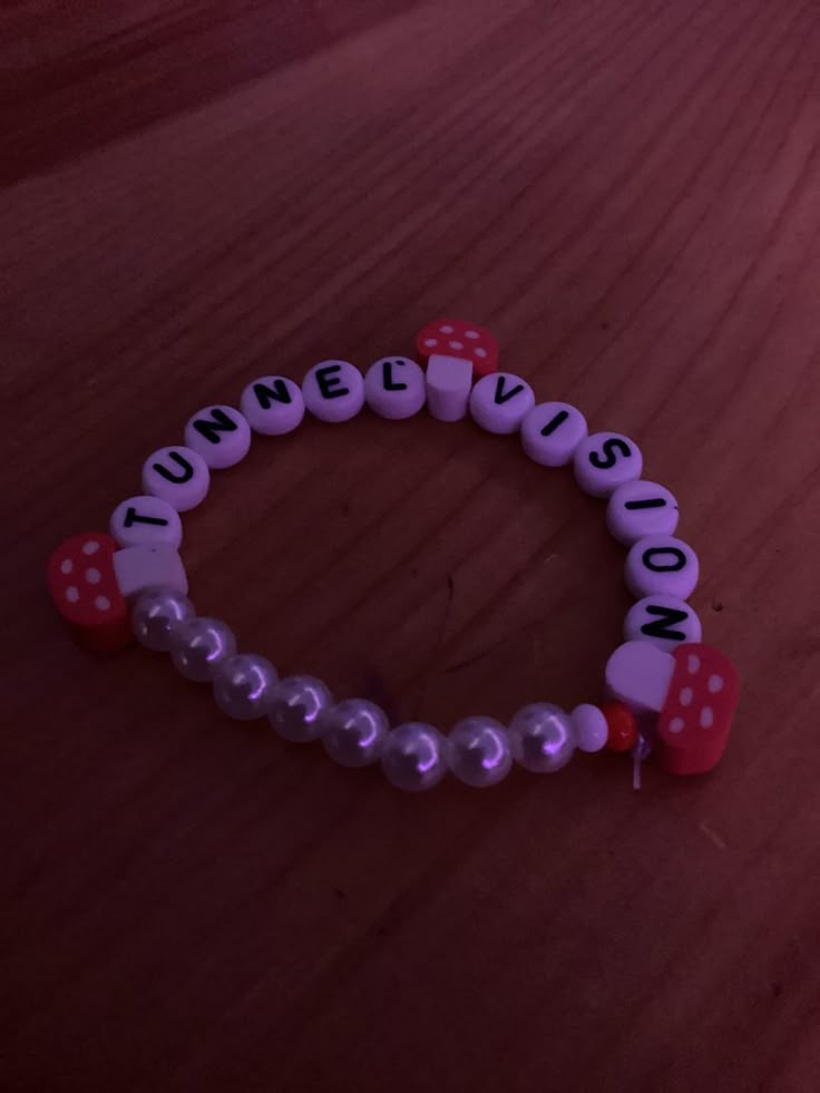 a close up of a beaded bracelet on a wooden surface with the word love spelled in small letters