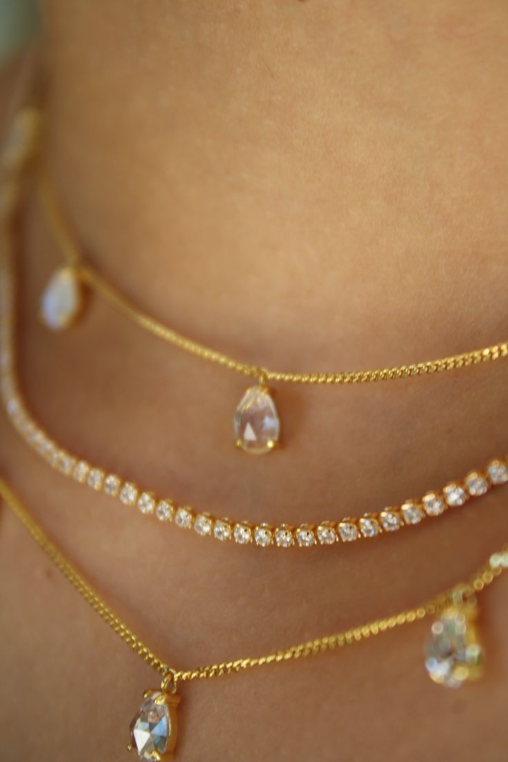 The Audrey Crystal Choker features five petite, rose cut pear crystal droplets on a dainty, 14k Gold Vermeil, very high quality curb chain. It features a 3” inch chain extender for layering flexibility. The droplets dangle, and effortlessly add an element of chic sophistication to even your most casual look.  Materials: 14k Gold Vermeil (2.5 microns of gold over a sterling silver base)  Chain Length: 14” + 3” inch chain extender (17” inches total)  Crystal: 5A Cubic Zirconia  How do I care for m Gold Moonstone Ring, Necklace Stack, Stacked Earrings, Stacked Necklaces, Gold Gemstone Ring, Birthday List, Chain Extenders, Crystal Choker, Tennis Necklace