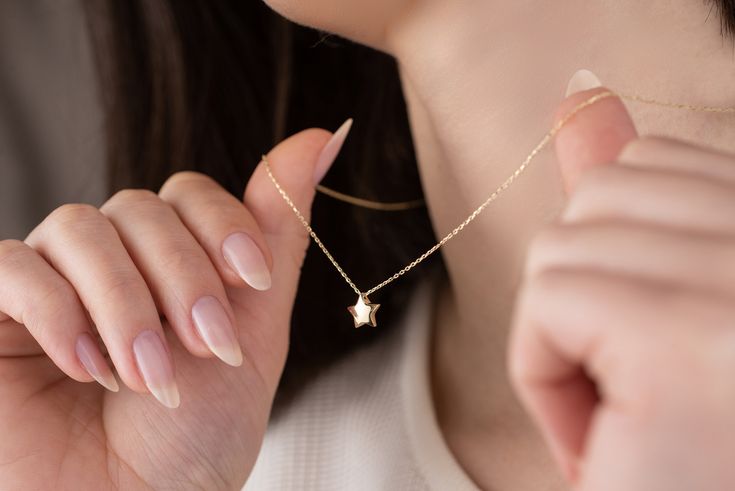 Our star charm necklace is made of 14k solid gold. It has a dainty and minimalist style that everyone from 7 to 70 loves it!  This small star will accompany you everywhere. It looks like a puffed star. (The front and back do not look the same.) The chain passes through one corner of the star. When you consider our minimalist gold star necklace as a gift, it will make your loved ones happy on their birthday, mother's day, valentine's day, anniversaries, graduation, or women's day. It will be a pe 14k Gold Star Necklace For Gift, 14k Gold Star Necklace As Gift, 14k Gold Star Necklace Perfect For Gifts, Dainty Star-shaped Necklace For Anniversary, Dainty Star Necklace For Anniversary, Dainty Star-shaped Anniversary Necklaces, Elegant Star-shaped Birthday Jewelry, Dainty Jewelry With Star Charm For Birthday, Dainty Star Charm Necklace For Anniversary