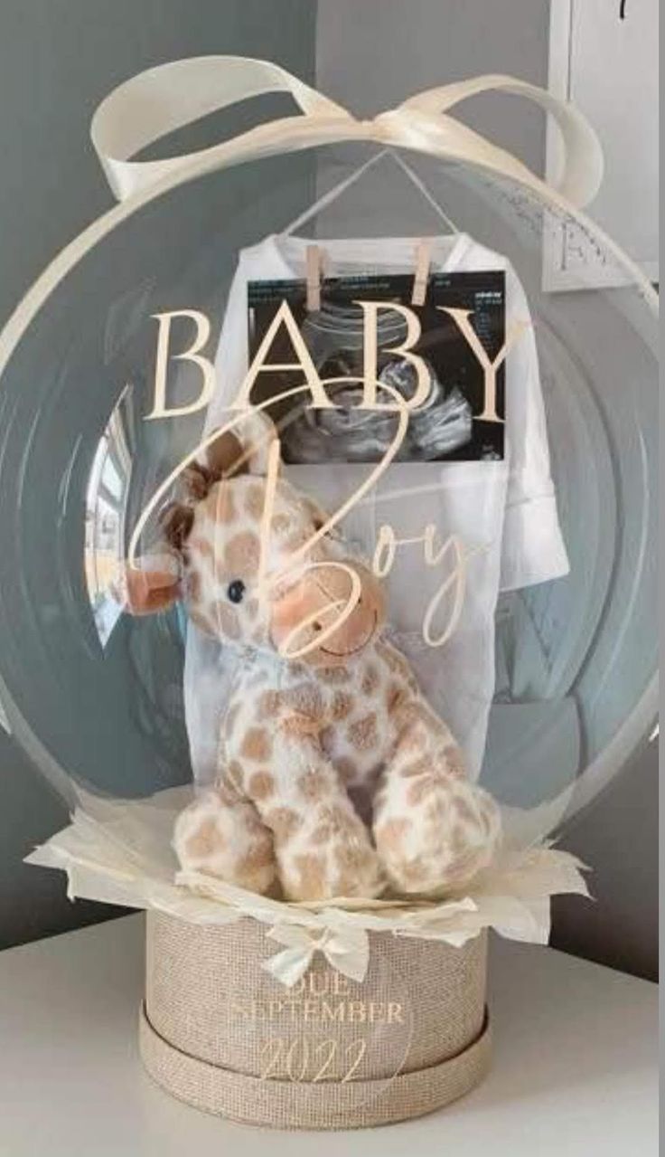 a stuffed giraffe in a glass ball with the word baby on it's label