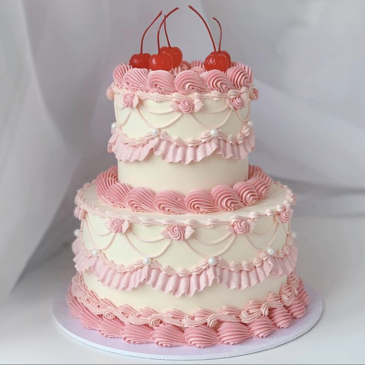 a three tiered cake with pink icing and cherries on top is shown