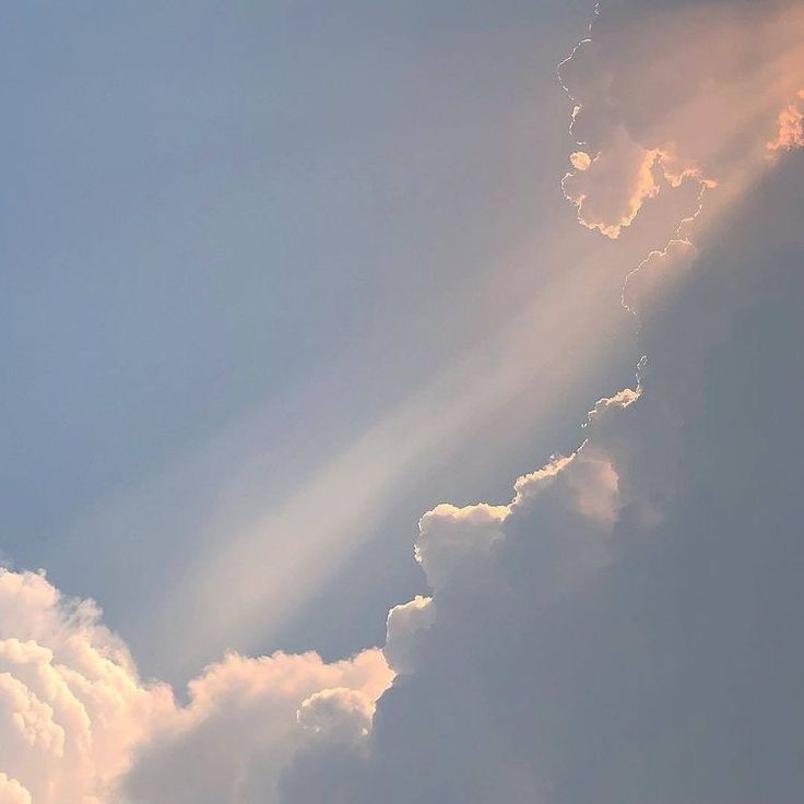 an airplane is flying in the sky with sun rays coming out from behind it's clouds