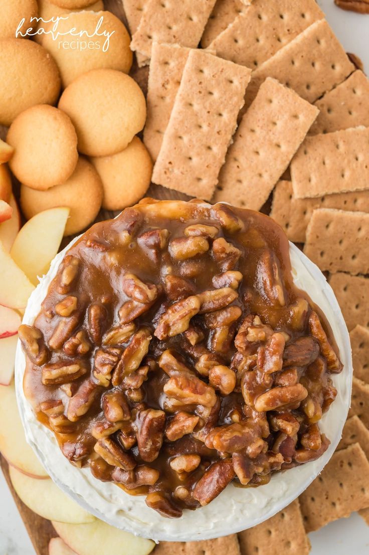 a plate with crackers, apples, and nuts on it next to crackers