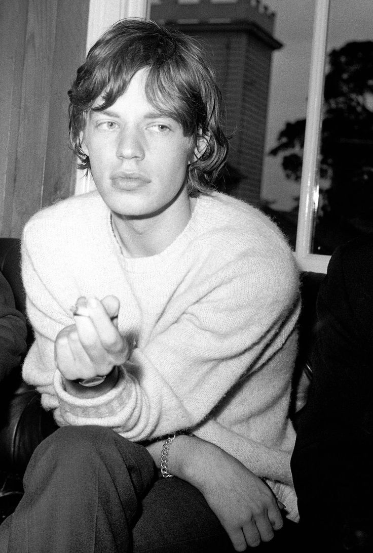 black and white photograph of young man sitting on couch with remote control in his hand