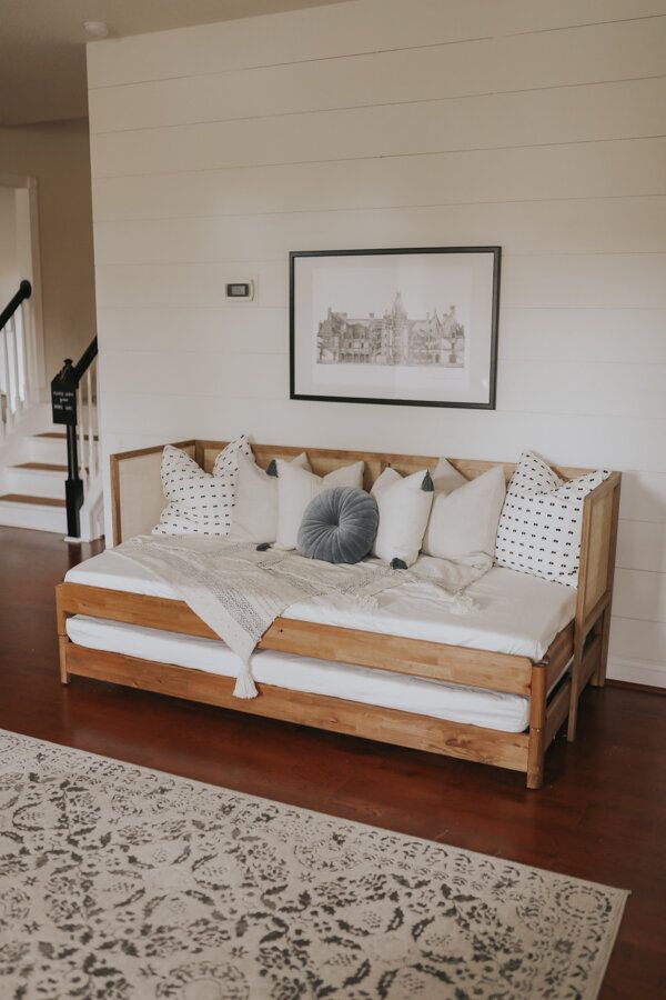 a bed sitting on top of a hard wood floor next to a stair case in a living room