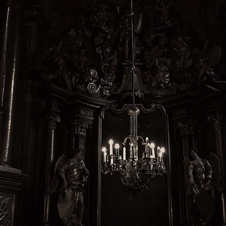 black and white photo of chandelier with candles in the dark room at night