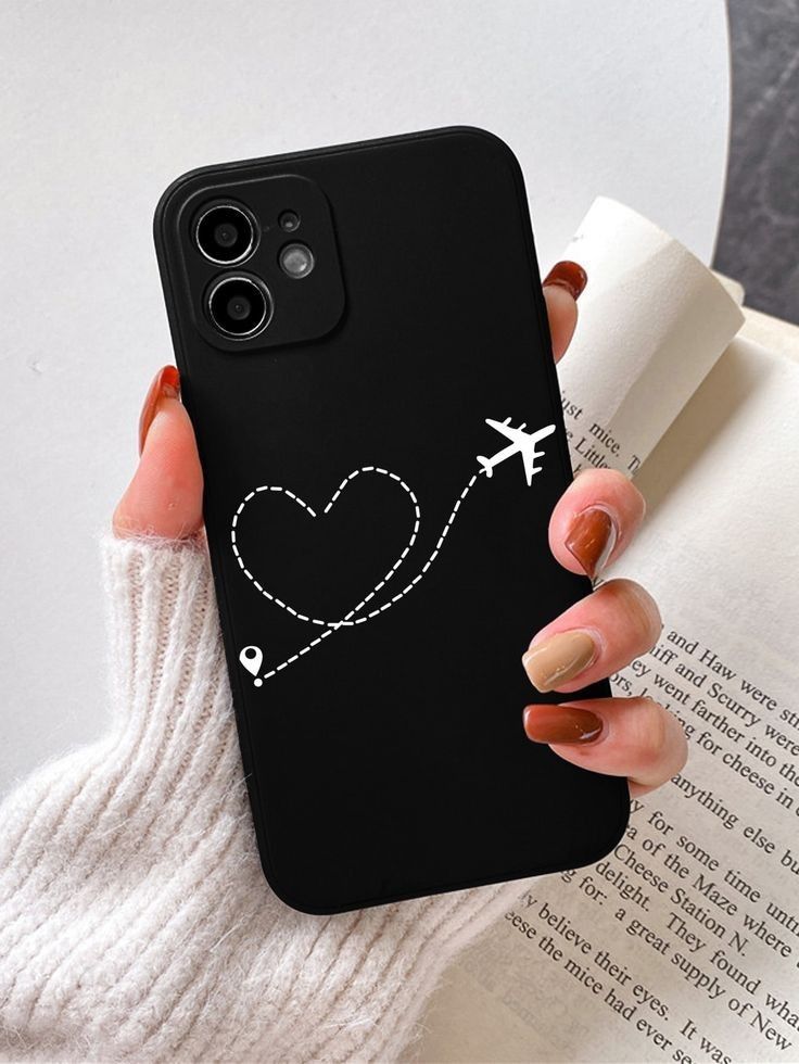 a woman holding up her phone case with an airplane and heart on it