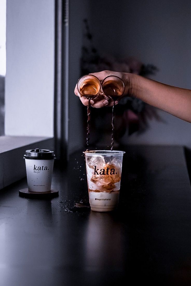 a person pouring coffee into two cups