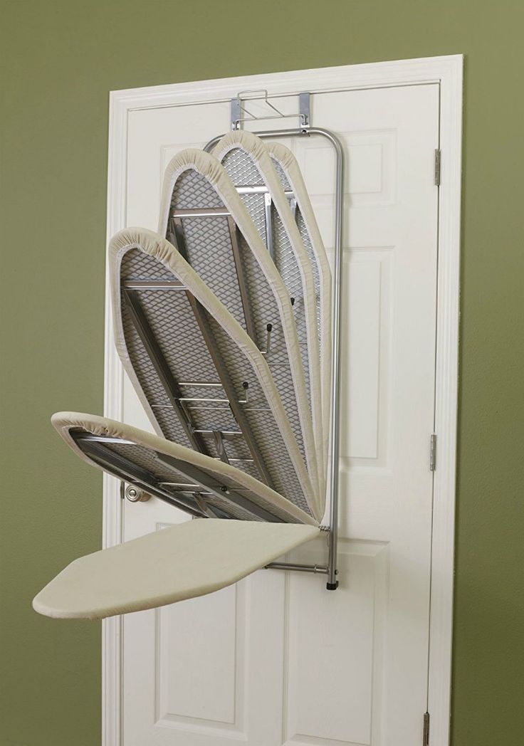 an ironing board is hanging on the wall next to a white door with four surfboards in it