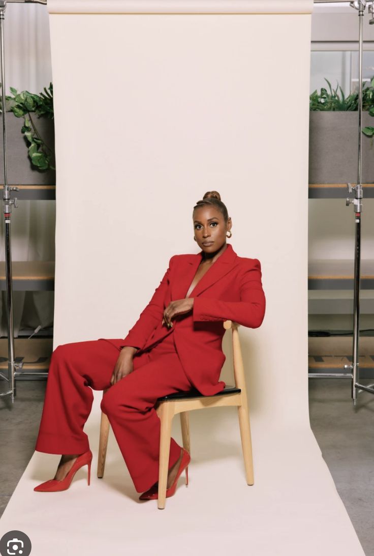 a woman in a red suit sitting on a chair