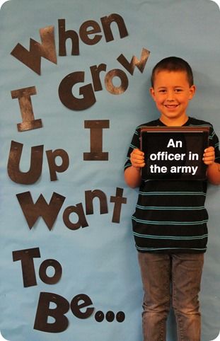 a boy holding up a sign that says when i grow up i want to be