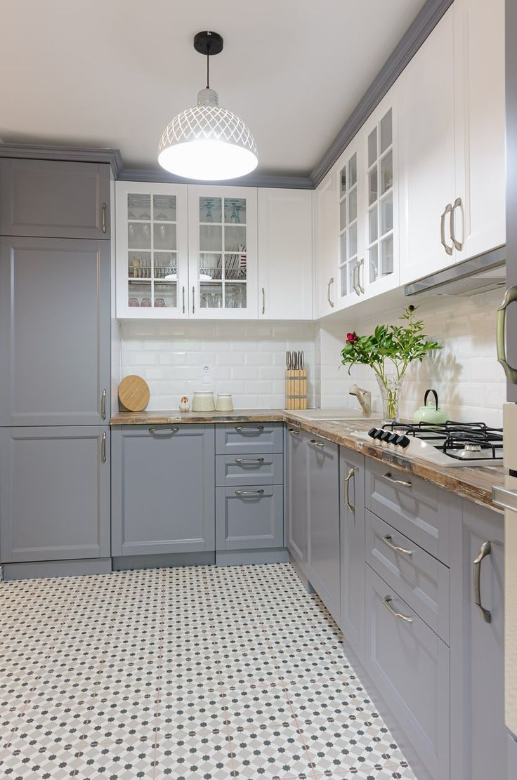 a kitchen with gray cabinets and white tile flooring