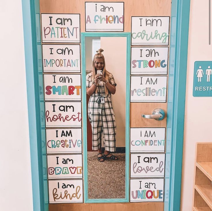 a woman taking a selfie in front of a mirror with words written on it