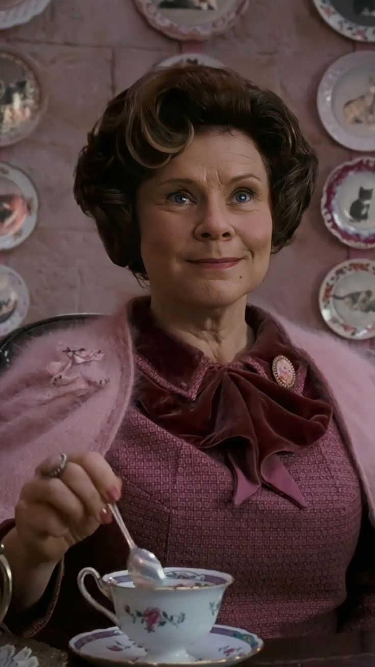 an older woman sitting at a table with a tea cup and saucer