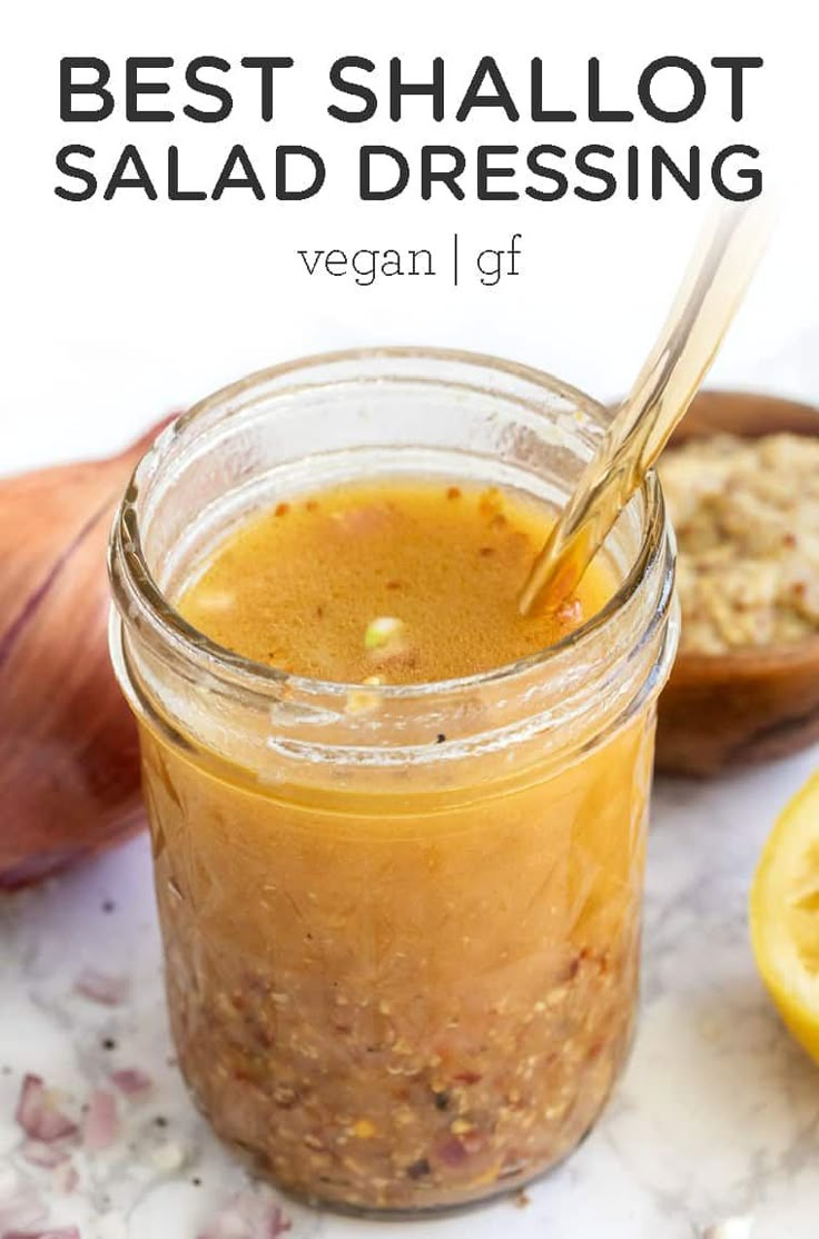 a glass jar filled with salad dressing next to sliced lemons