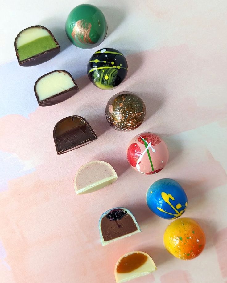 there are many different types of chocolates on the table with pink and blue background