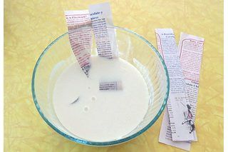 a glass bowl filled with white liquid next to two pieces of paper