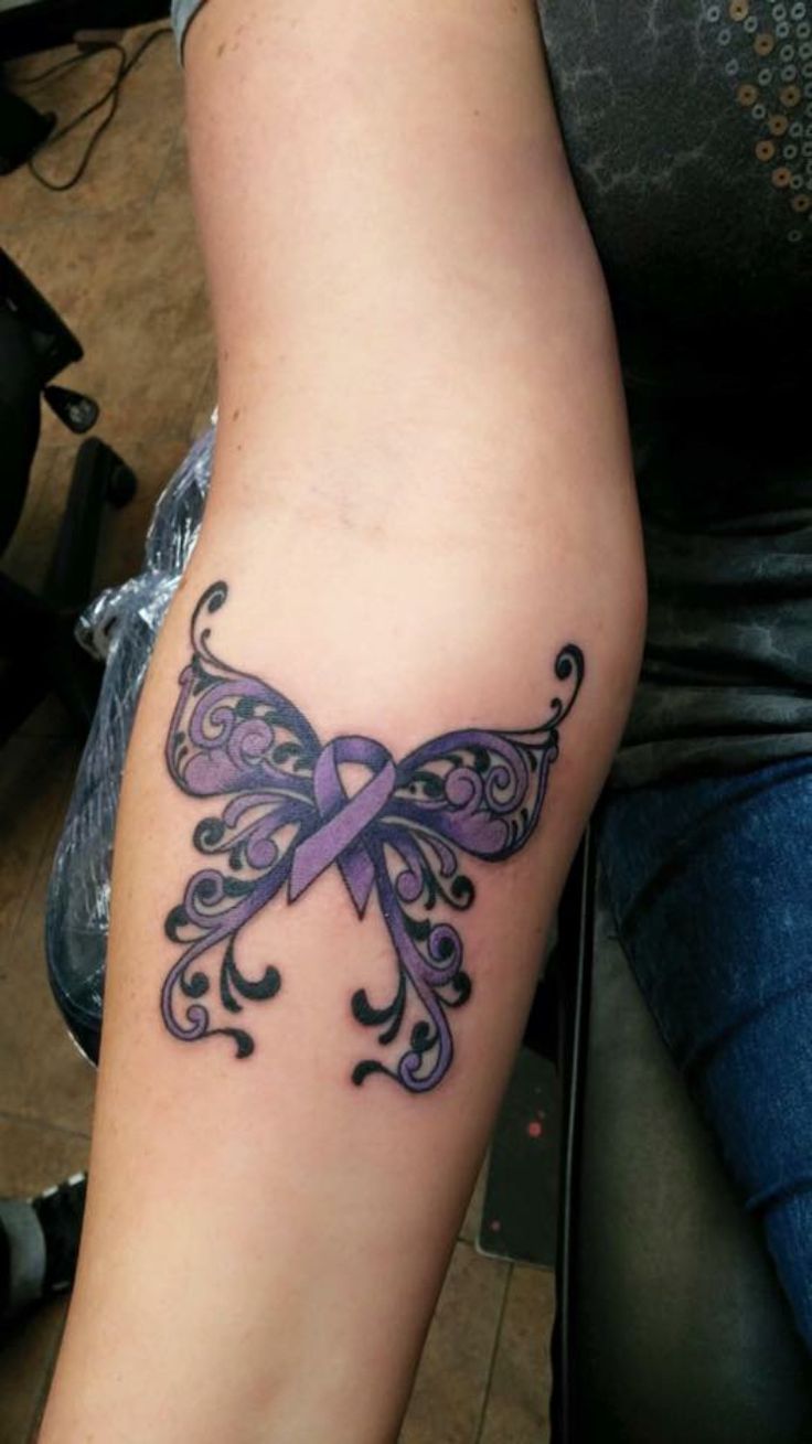 a woman's arm with a purple ribbon tattoo on the left side of her arm