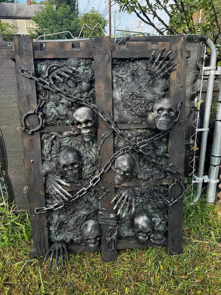 a large metal door with skeleton hands and chains on it's sides, in the grass