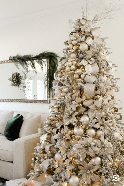 a white christmas tree with gold and silver ornaments in the corner, next to a couch