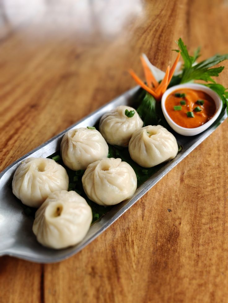 some dumplings are sitting on a plate with dipping sauce