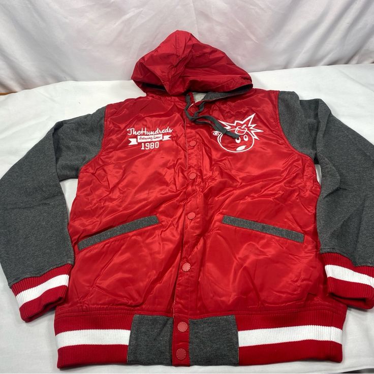 Brand New In With Tags The Hundreds X Drawing Lines Reloaged Sp 13 Varsity Jacket Size: Men's Medium Features: Vintage Letterman Retro Sport Styling Snap Front Closure Red Body With Grey Fleece Sleeves Adjustable Red Hood With Gray Fleece Lining And Drawstrings Embroidered White Adam Bomb Left Chest The Hundreds Drawing Lines 1980 Text Right Chest Huge Text In Rear 2 Front And 1 Inner Right Side Pockets Red & White Striped Rib Knit Cuffs And Hem Charcoal Lining Questions? Leave A Comment Below! Vintage Red Track Jacket For Winter, Red Vintage Track Jacket For Winter, Red Vintage Winter Track Jacket, Retro Red Hooded Windbreaker, Retro Red Hooded Outerwear, Red Retro Hooded Windbreaker, Retro Red Sports Outerwear, Red Sporty Varsity Jacket With Pockets, Casual Red Hooded Varsity Jacket