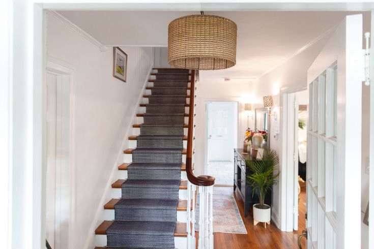 a staircase with carpeted steps leading up to the second floor and another room in the background