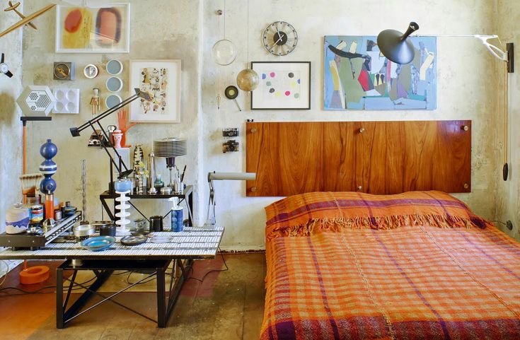 a bed sitting in a bedroom next to a wooden table and wall with pictures on it