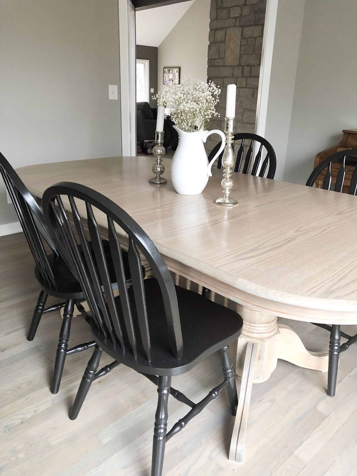 a dining room table with black chairs and a white pitcher