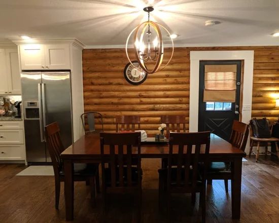 a dining room table and chairs in front of a kitchen with wood paneled walls