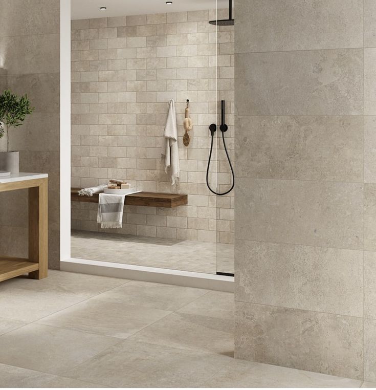 a bathroom with a walk in shower sitting next to a sink and a wooden table