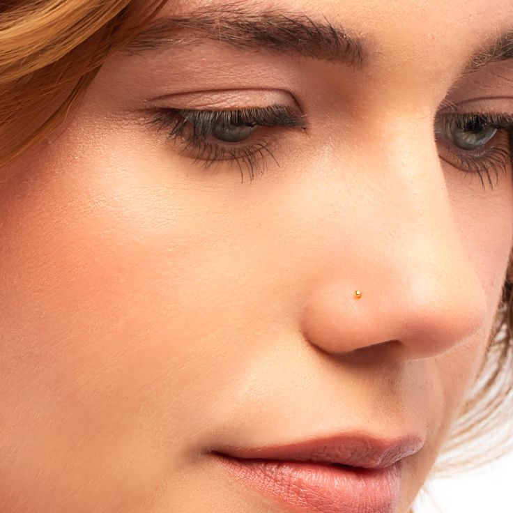 a close up of a woman's face with her eyes closed and nose piercing