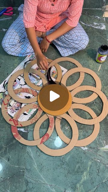 a woman sitting on the floor working on an art project with cardboard circles and glue