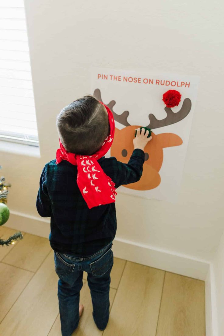 a little boy that is standing in front of a christmas tree with a reindeer on it