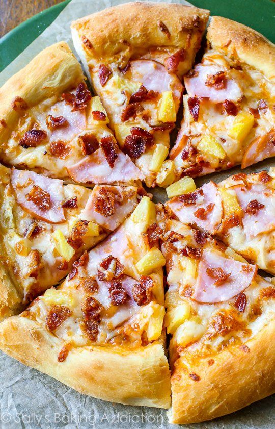 a pizza with pineapple and bacon on it is cut into eight slices, sitting on a green platter