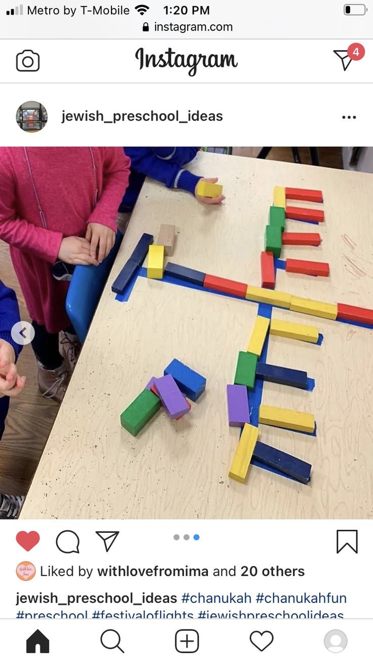 two children are playing with wooden blocks on the table and one child is pointing at them