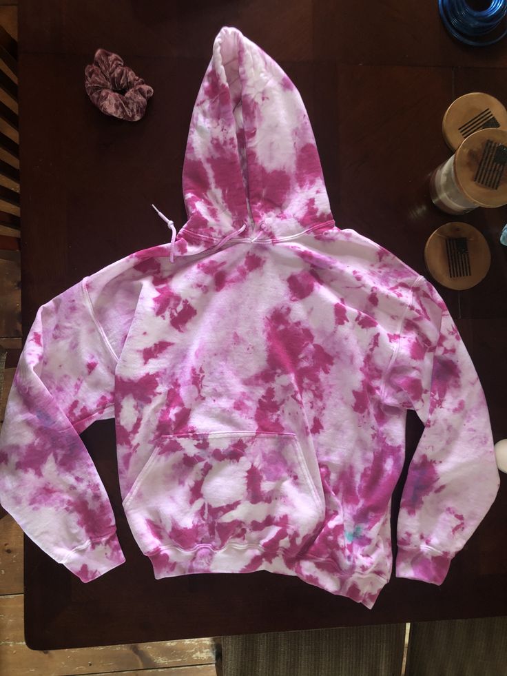 a pink and white hoodie sitting on top of a table next to other items