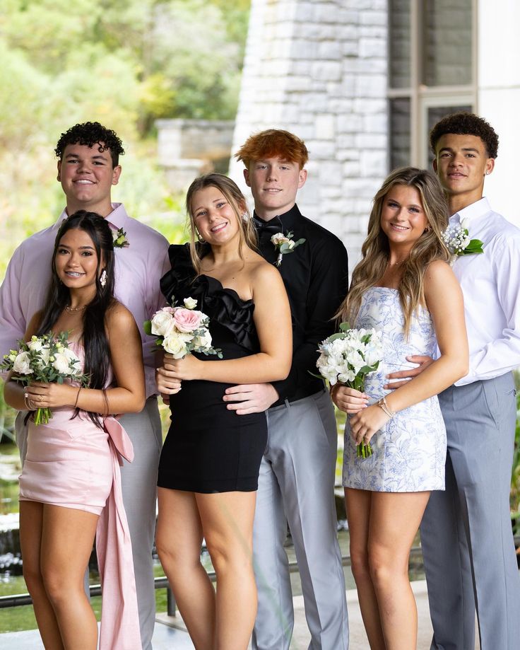 a group of people standing next to each other in front of a building with flowers