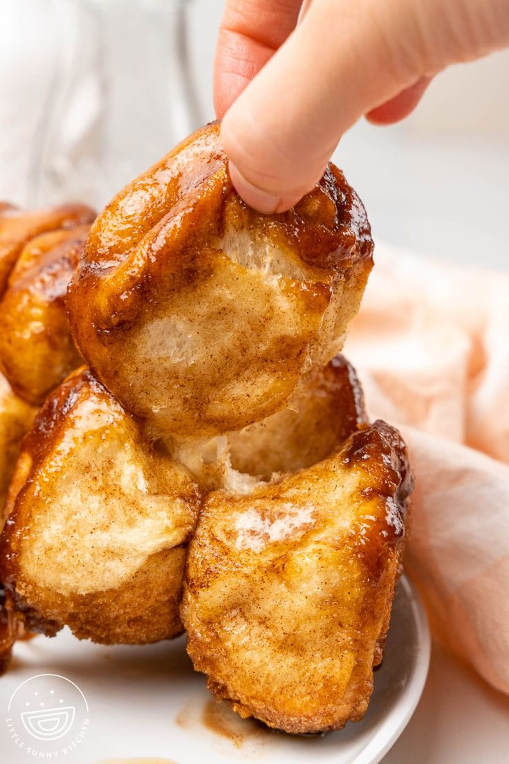 a person picking up some fried food from a plate