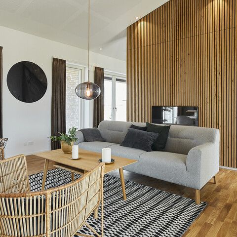 a living room filled with furniture next to a wooden table and wall covered in wood slats