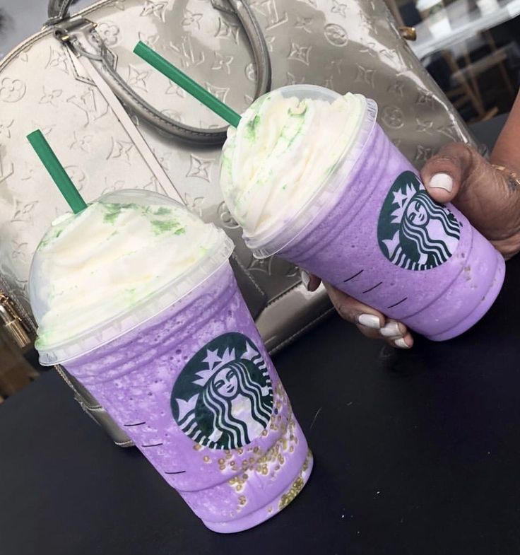 two starbucks drinks are sitting next to each other on a table in front of a purse