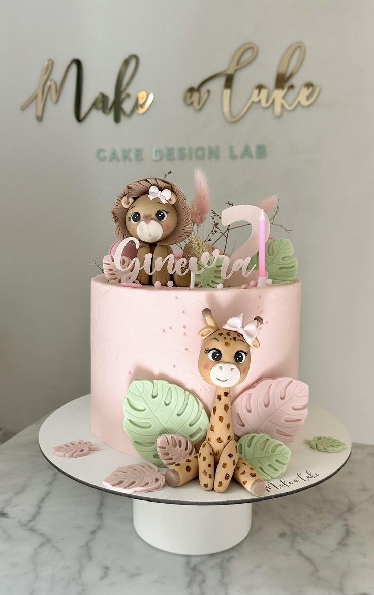 a pink cake with giraffes and leaves on it