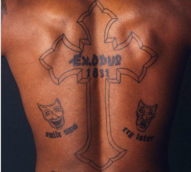 the back of a man with tattoos on his upper and lower body, showing different symbols