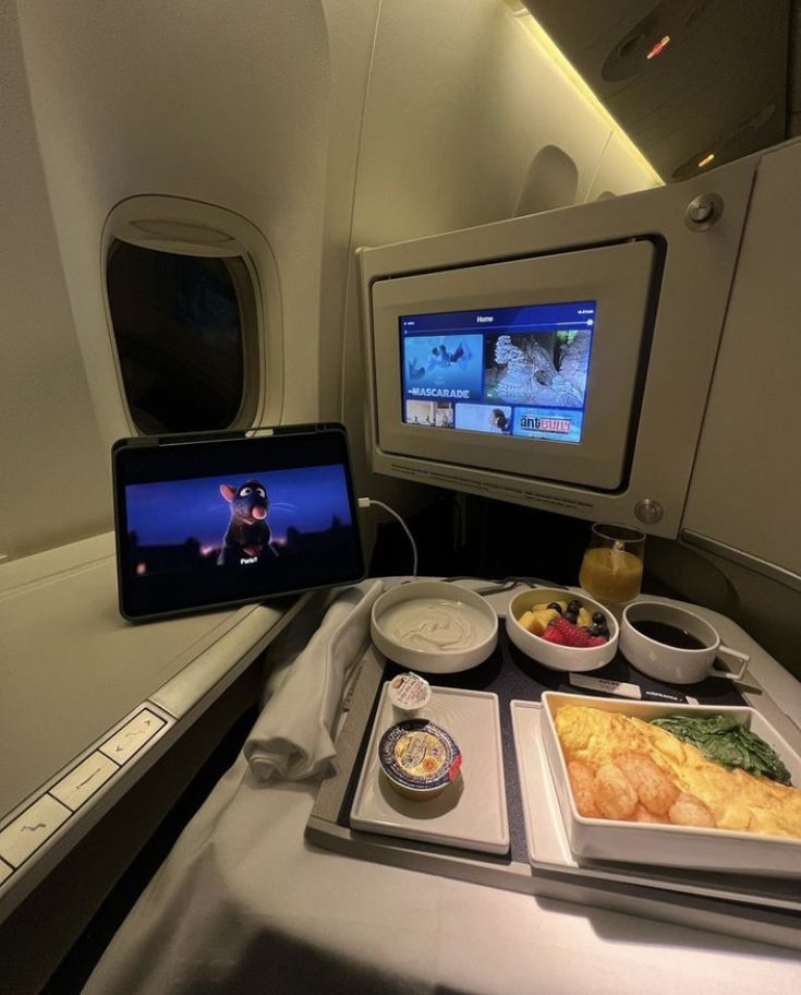 an airplane tray with food on it and a laptop in the middle, along with other items